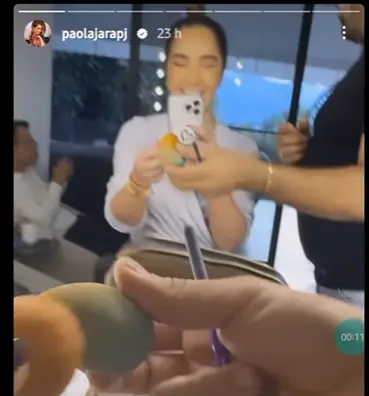 Paola Jara cmiendo buñuelo mientras la maquillan. Imagen tomada de Instagram